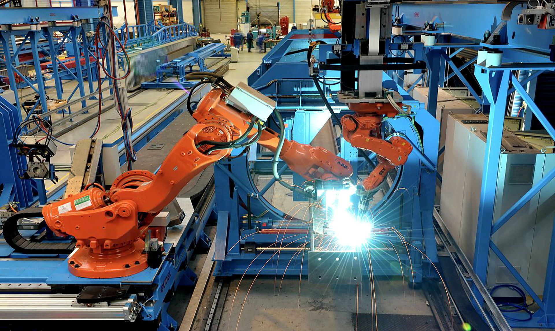 Industrial robot welding a steel assembly in a fabrication cell