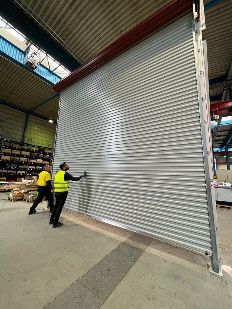 Installers fitting a large roller door in an industrial building
